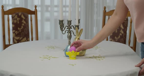 the Woman's Hand Places on a Table a Support with a Pink Painted Egg