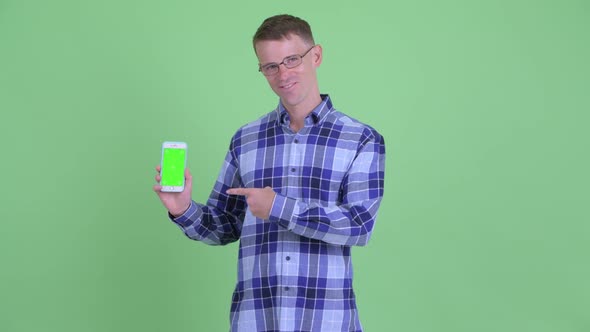 Portrait of Happy Hipster Man Showing Phone and Giving Thumbs Up