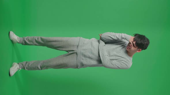 Full Body Of Asian Man Having Headache While Standing In Front Of Green Screen Background