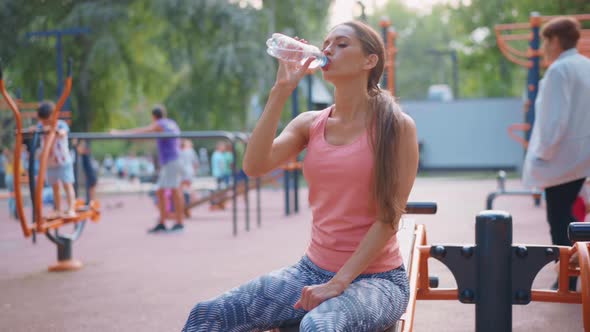 Sportive Woman Sitting Summer Day on Sport Ground Resting After Hard Training Drink Water Plastic