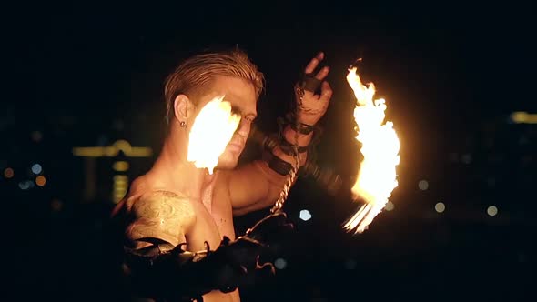 Young Blond Male Spins Two Burning Pois Tied Together. Slow Motion Shot. Close-up Shot.