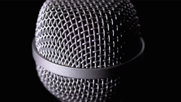 The Microphone Rotates on a Black Background. Dynamic Microphone Grid Spins Close-up