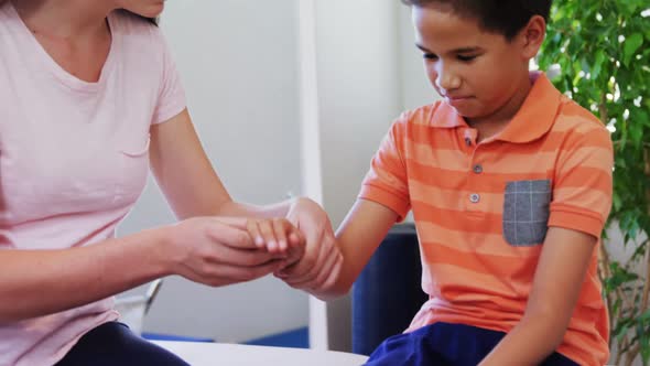 Female physiotherapist giving hand massage to boy patient 4k