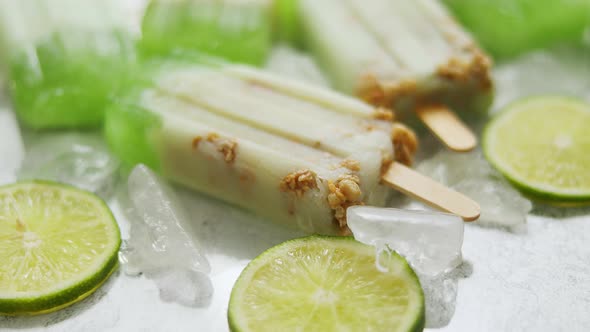 Lime and Cream Homemade Popsicles or Ice Creams Placed with Ice Cubes on Gray Stone Backdrop