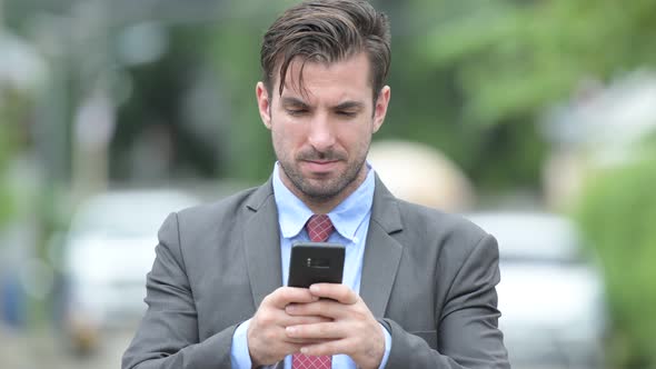 Young Happy Hispanic Businessman Using Phone Outdoors
