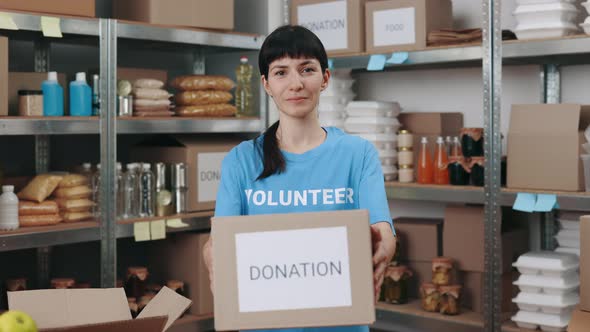 Female Volunteer Holding Donation Box at Warehouse