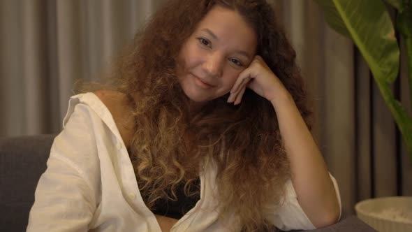 Satisfied Mixed Race Lady with Curly Hair Looks Straight