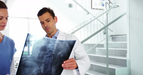 Doctor and nurse discussing over x-ray report in corridor