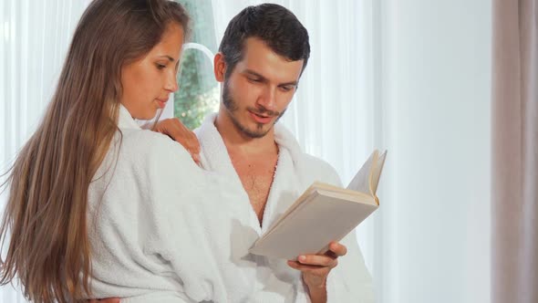 Happy Couple Wearing Bathrobes Reading a Book Together 1080p