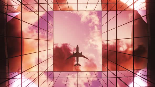 Passenger Plane Flying in the Sky with Clouds Over a Modern Glass Building at Sunset