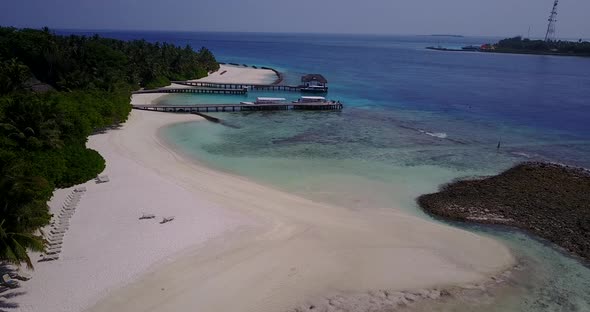 Daytime aerial island view of a white paradise beach and blue ocean background in hi res 4K