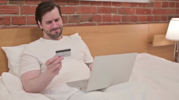 Casual Young Man with Unsuccessful Online Payment on Laptop in Bed