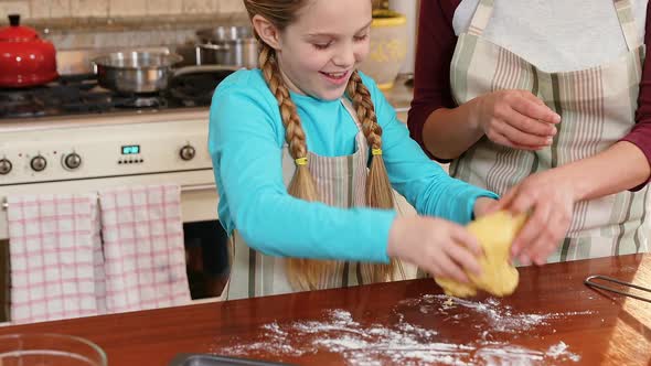 Smiling daughter kneading dough while mother standing besides her 4K 4k