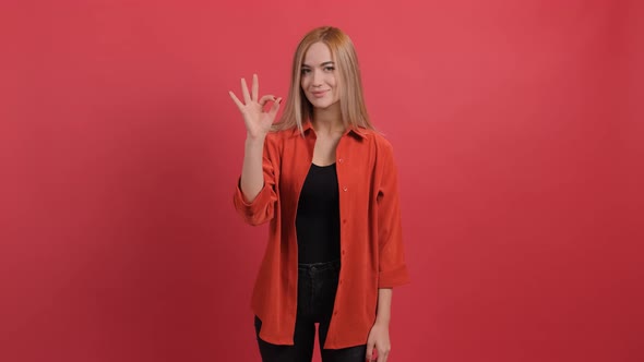 Young Woman Showing Ok Sign with Fingers Isolated on a Red Background