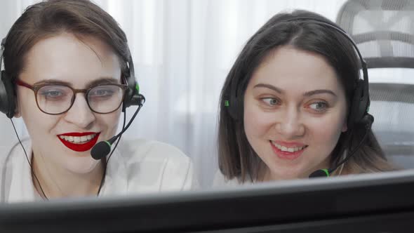 Cropped Shot of Two Female Call Center Operators with Headsets Using Computer