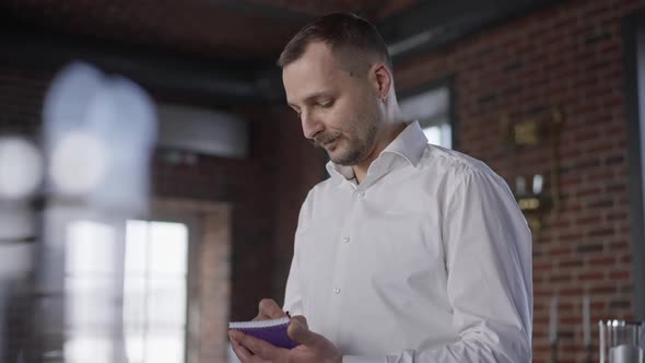 Male Caucasian Waiter with Mustache Writing Order Listening to Clients Standing in Luxurious