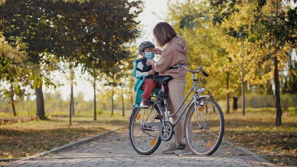 Mom Puts on a Medical Mask To Little Son Before Cycling