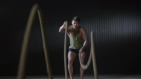 Motivated Sportsman Exercising with Battle Ropes