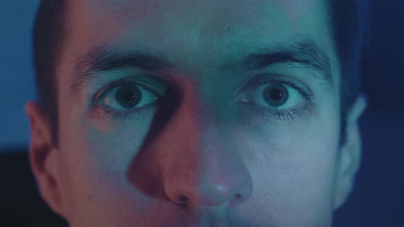 Close Up Young Man Watching a Horror Video or Film on TV or a Computer Monitor at Home