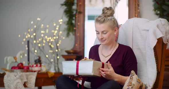 Woman Holding Present While Sitting On Chair At Home