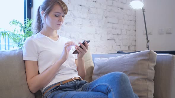 Woman Browsing Internet on Smartphone, Sitting on Couch