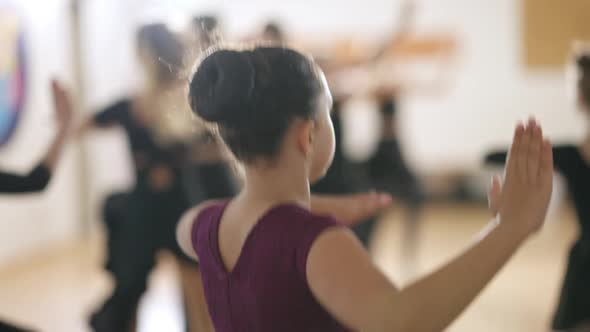 Brunette Caucasian Girl with Brown Eyes Jumping and Spinning in Fourth Position in Dancing School