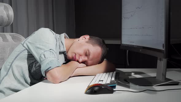 Man Smiling in His Sleep Resting on the Desk in Front of the Computer