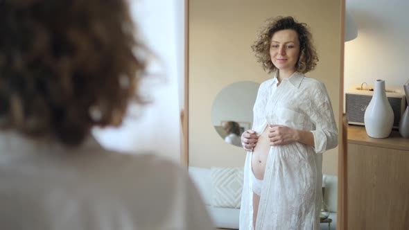 Pregnancy, Motherhood, People And Expectation Concept - Happy Pregnant Woman Looking To Mirror At