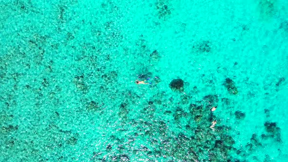 Wide aerial island view of a sandy white paradise beach and aqua blue ocean background in colourful 