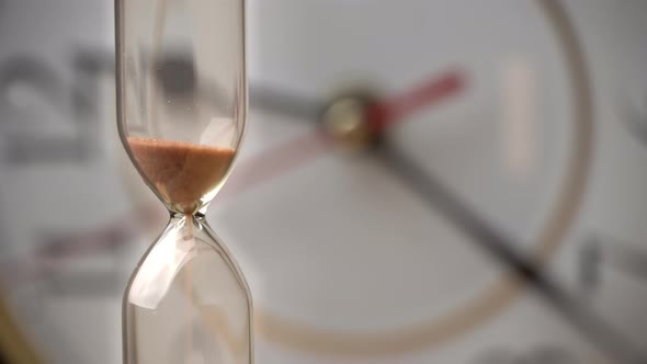 Hourglass Closeup is Pouring Against the Background Ordinary Mechanical Watch