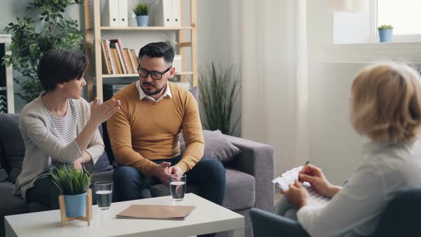 Angry Young Woman Talking To Husband in Psychotherapist's Office During Session