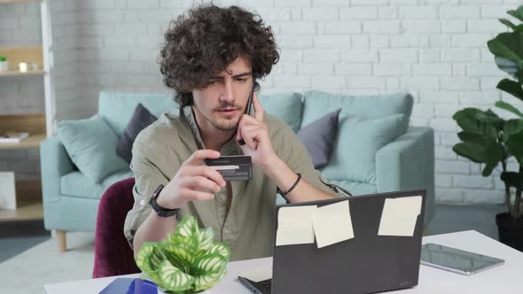 Guy Talking on Phone and Reading Credit Card Number While Working