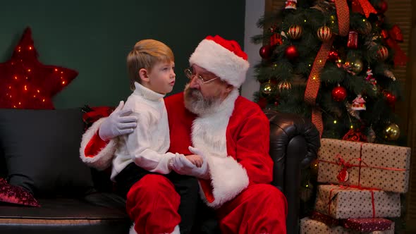Santa Claus with Little Boy Sitting on His Lap and Talking About His Dreams