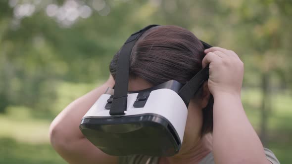 Closeup Young Woman with Dwarfism Putting on VR Headset in Slow Motion Standing in Spring Summer