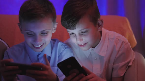 Two Cute Boys Playing Video Game with Smart Phone Indoors