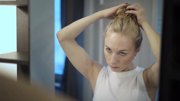 Handheld Shot of Blond Woman Straighten Hair with Hands