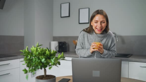 Woman Standing in Home Cozy Kitchen Leaning Over the Table and Communicates Via Video Link with