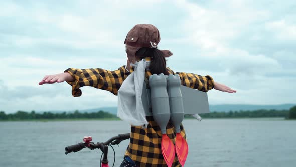 Funny Asian child girl playing with toy rocket sitting on bicycle and raised arms, Kid play outdoors