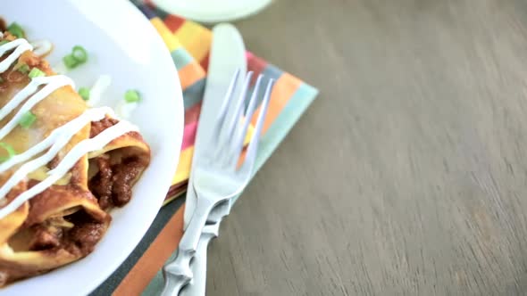 Close up of dinner plate with Chicken enchiladas garnished with green onions and sour cream.