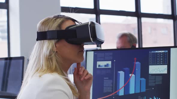 Caucasian businesswoman using vr headset at desk in office