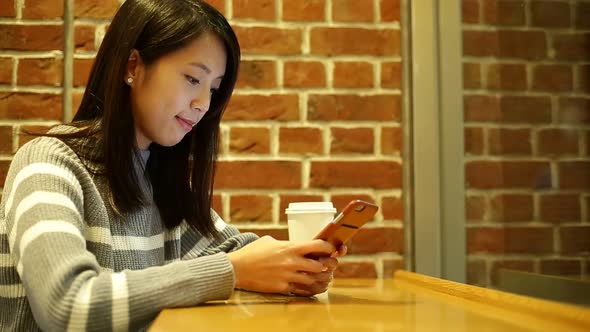 Woman using cellphone at night inside coffee shop 