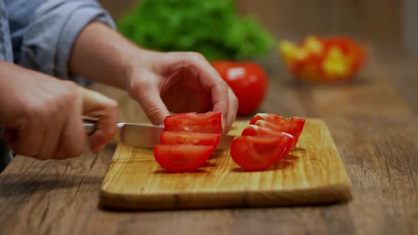 man cuts red tomatoes. cooking process by the chef. salad ingredients. caring man preparing dinner