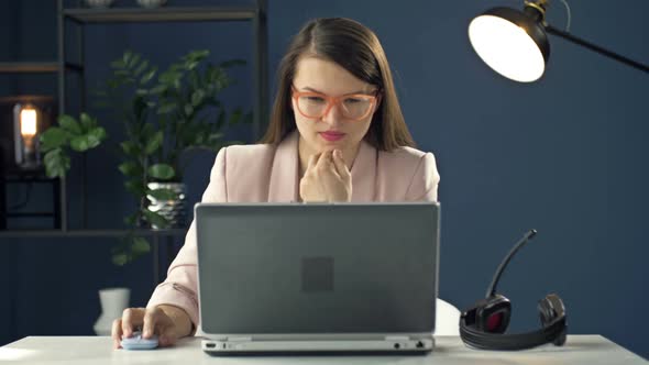 Portrait of a Young Woman in a Headset Working at a Laptop