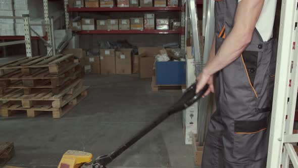 Factory Man Is Loading Cardboard Boxes on a Hand Pallet Truck in Warehouse