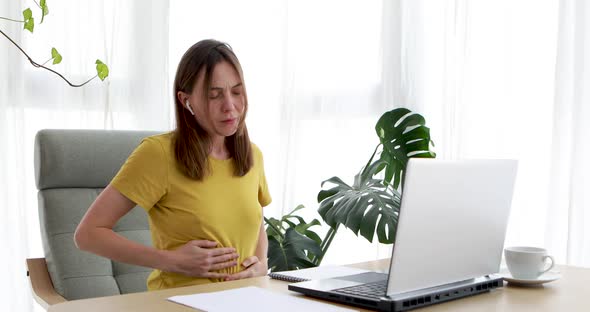 Woman Working at Home on Laptop Feels Stomach Pain