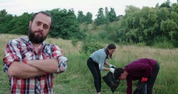 Happy Man Looks and Crosses Hands at Camera at a Youngs Collecting Garbage