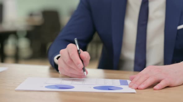 Close Up of Hands of Businessman Writing on Paper