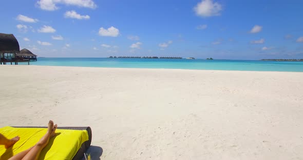 Aerial view of a couple lounging on a beach at a tropical island resort hotel.