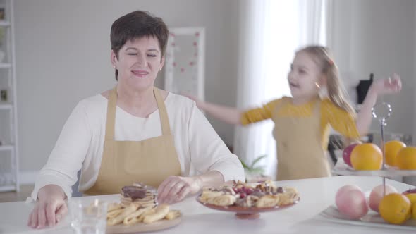 Portrait of Positive Adult Caucasian Woman Smiling at Camera As Little Cheerful Girl Running To