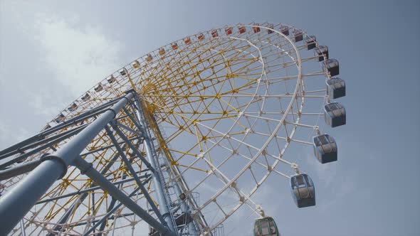 Big Ferris Wheel Rotates at Amusement Park Ride Over Clean Blue Sky